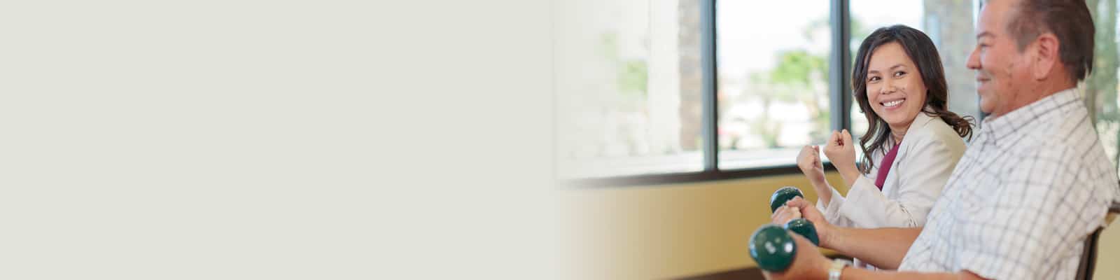A rehabilitation therapist working with a man lifting weights