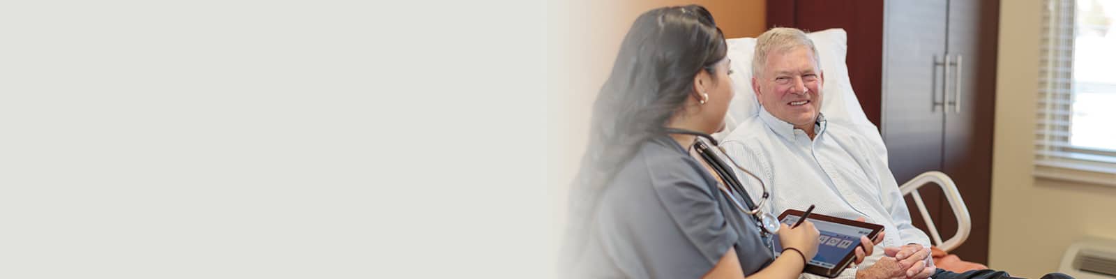 A nurse helping a patient laying in bed at Canyon Vista Post Acute